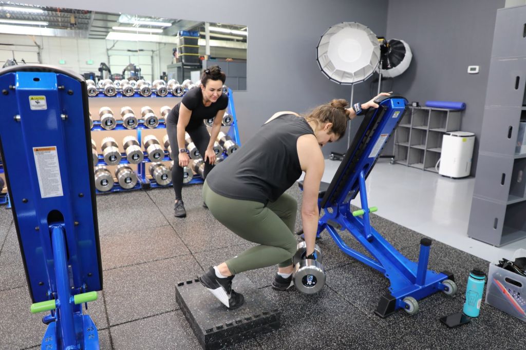 Val coaching a client through a dumbbell exercise in the gym