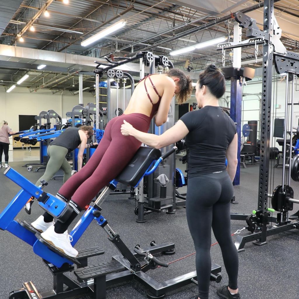 Val spotting a client on a glute machine in the gym